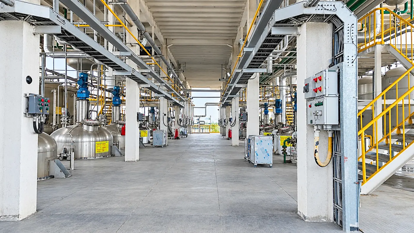 Reactor hall at the DECHEM manufacturing base: stainless steel reactors, agitator drives and overhead pipe racks